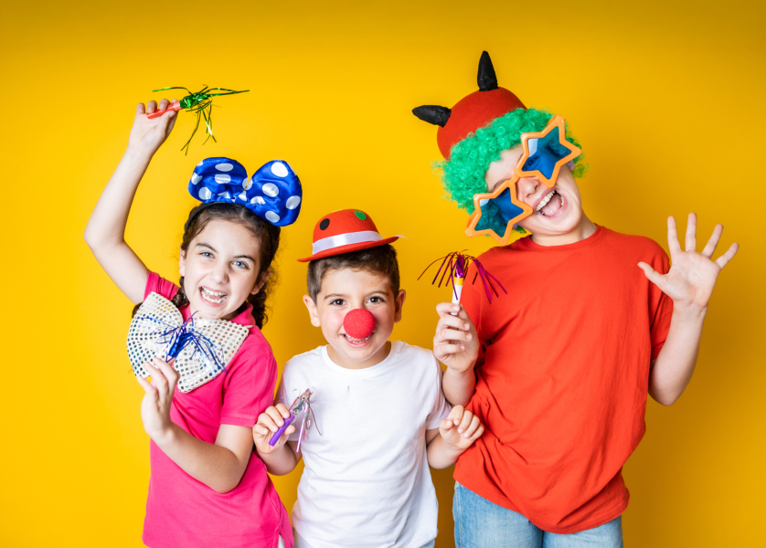 Three kids celebrating Carnival or New Years Eve at home